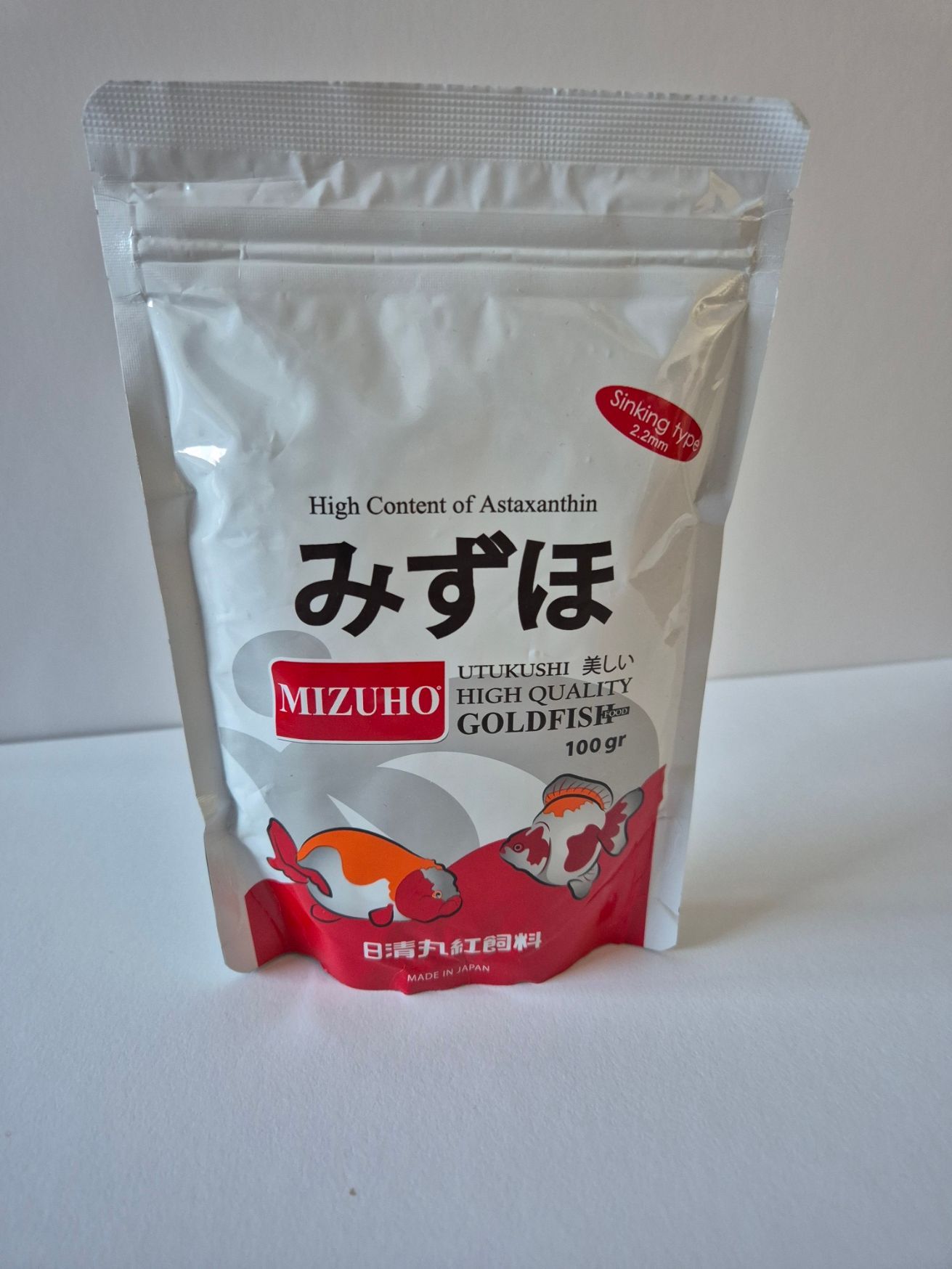 Witte zak Mizuho hoogwaardig goudvisvoer, met goudvisafbeeldingen in rood en wit.