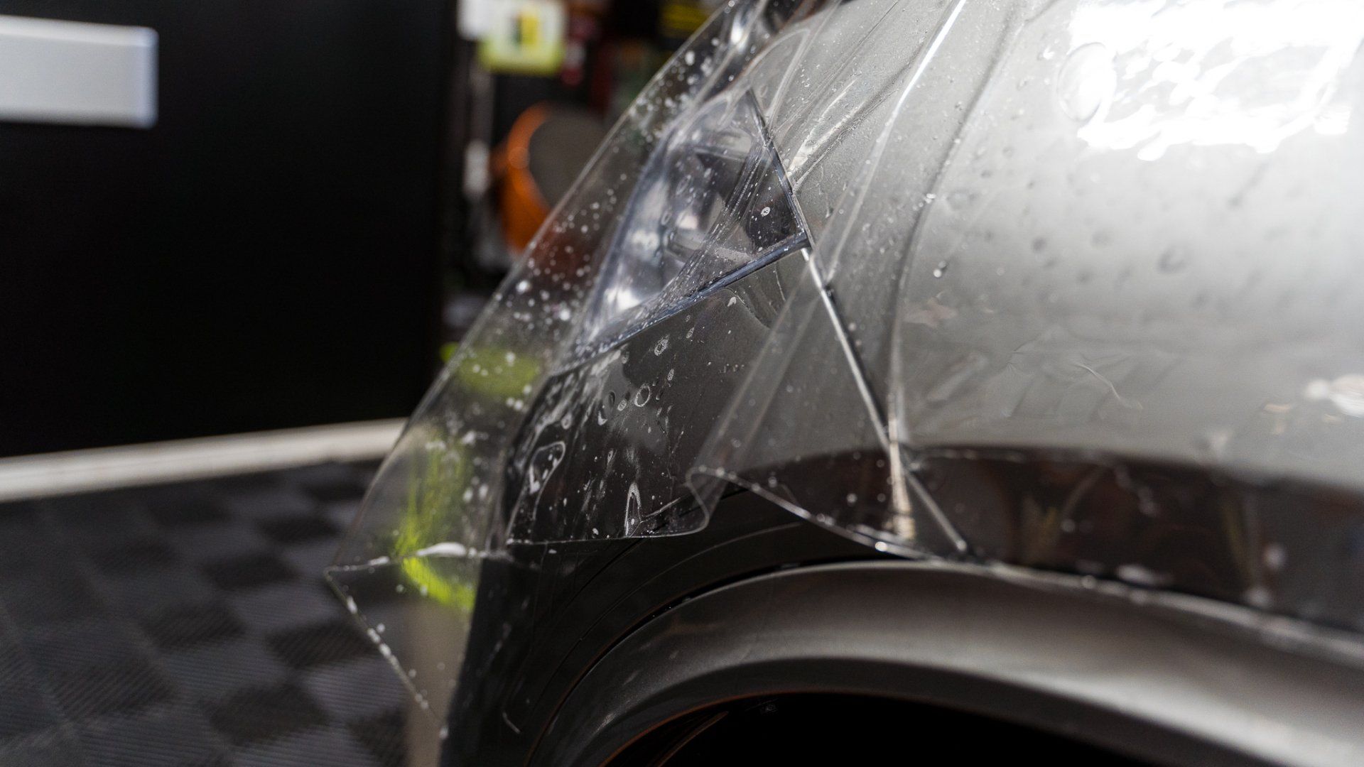 Clear protective film being applied to a car's silver fender.
