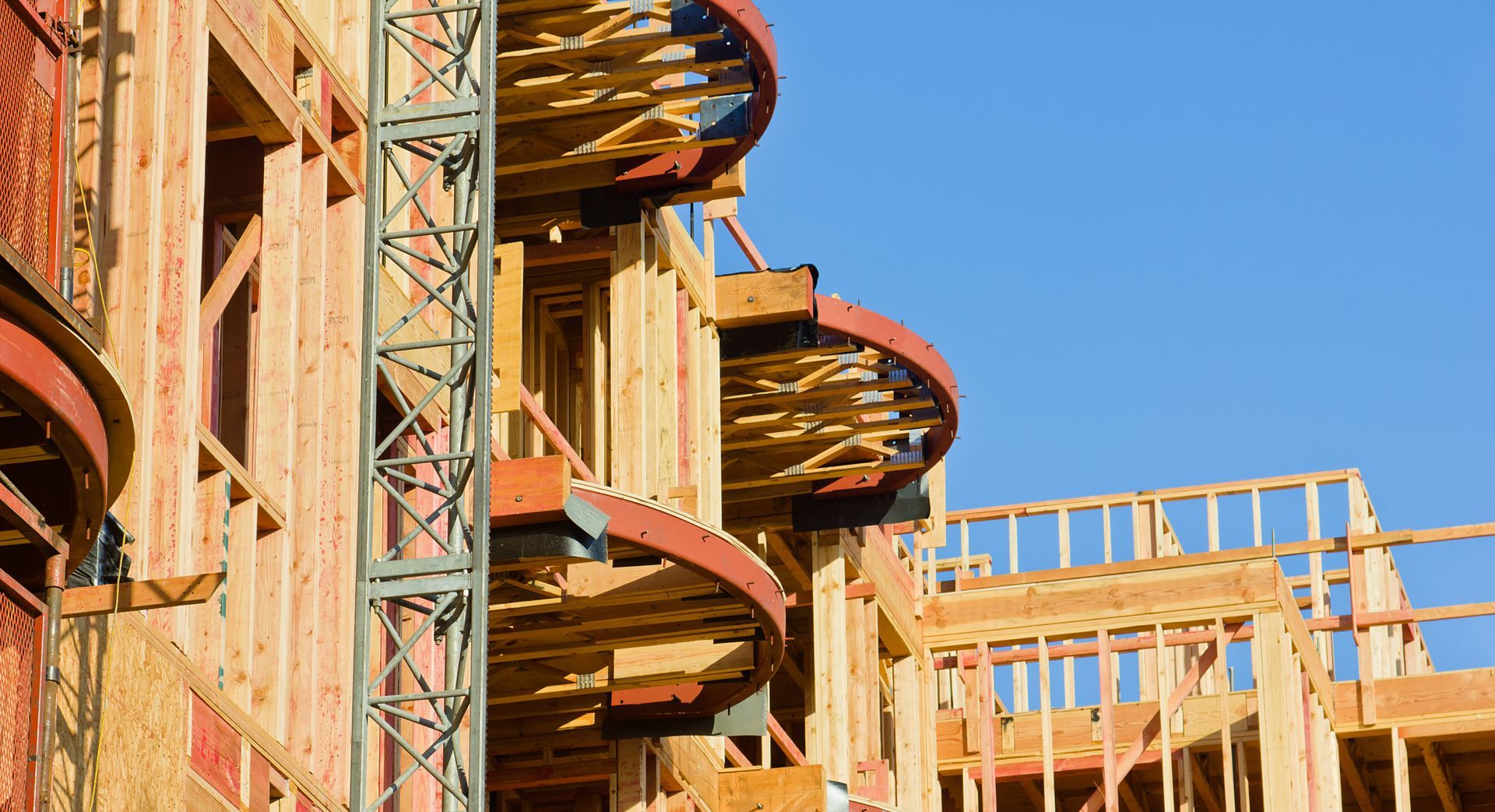 A large wooden building is being built with a crane in the background.