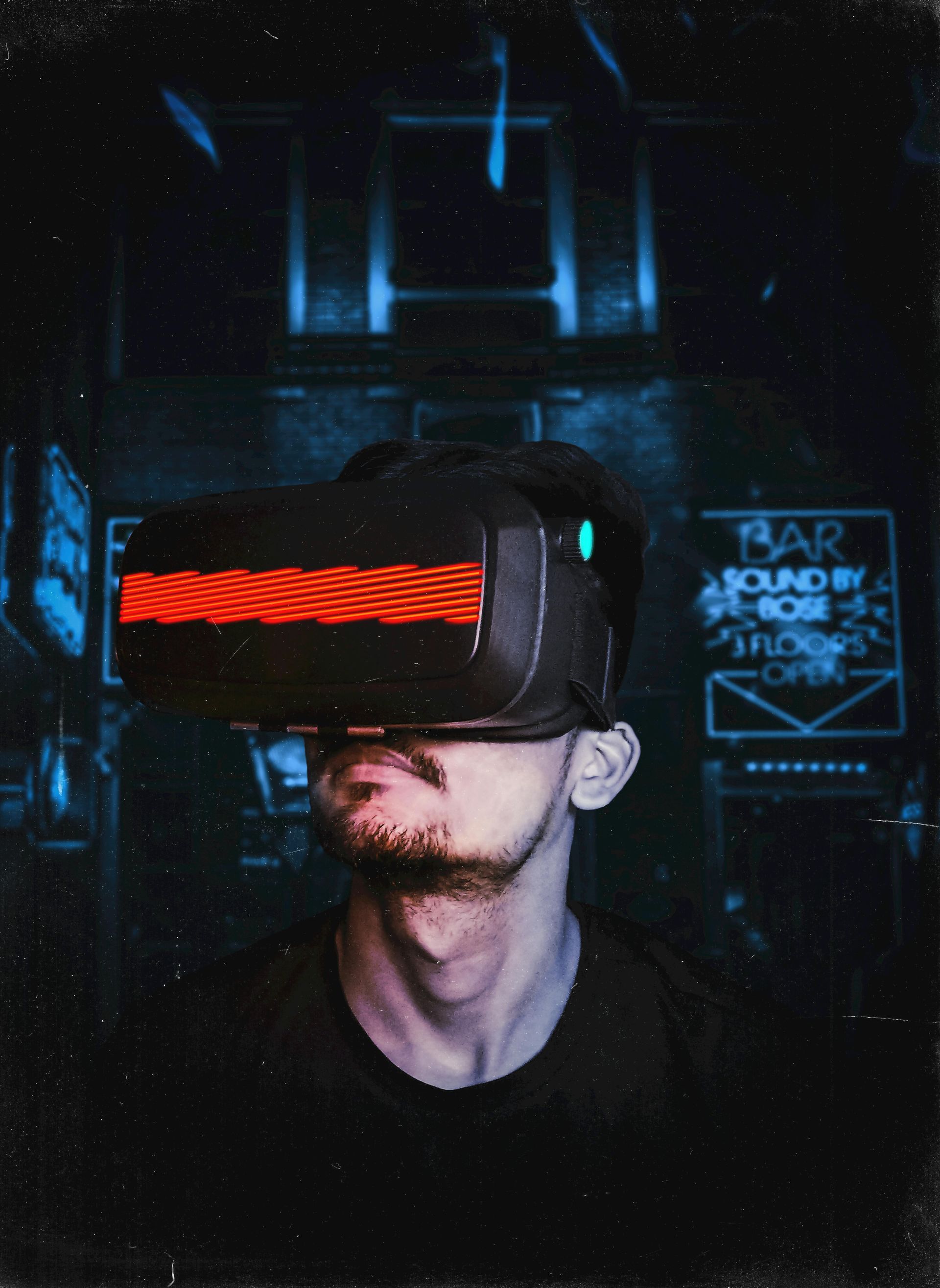Man wearing VR headset, red/black, in dimly lit bar.