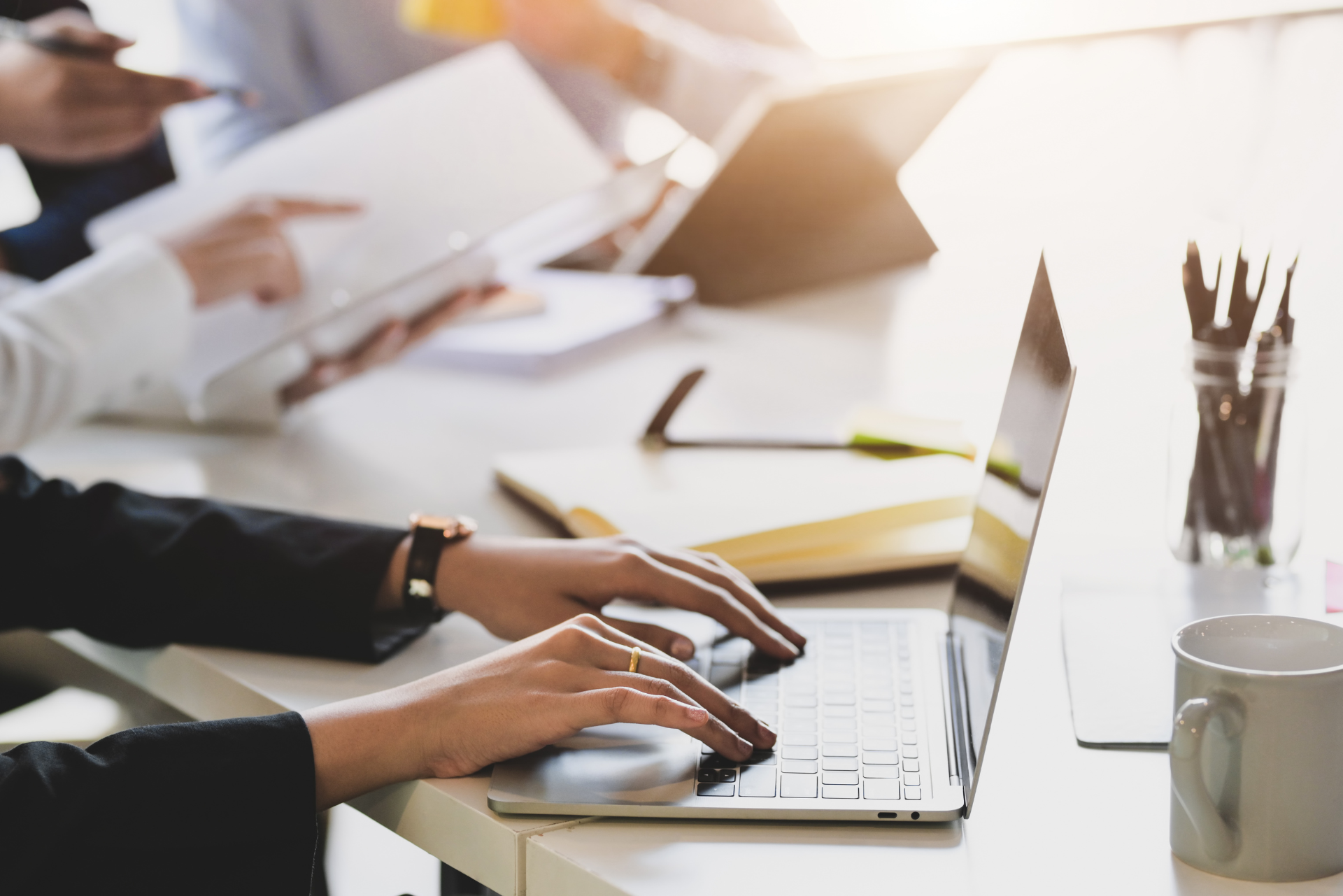 Una persona está escribiendo en una computadora portátil en un escritorio.