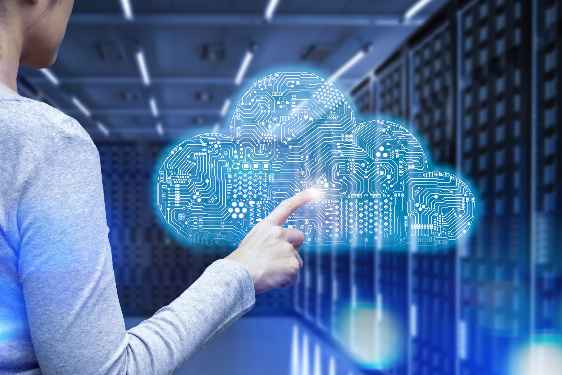 Una mujer señala una nube en una sala de servidores.