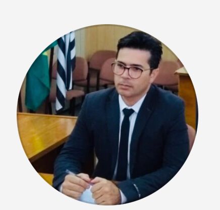 Um homem de terno e gravata está sentado à mesa