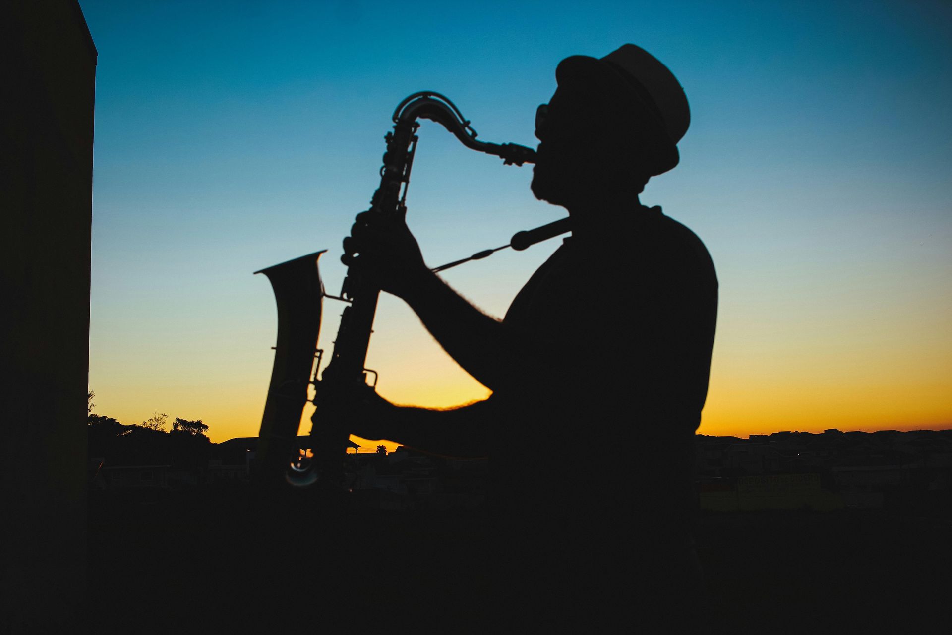 Uma silhueta de um homem tocando saxofone ao pôr do sol