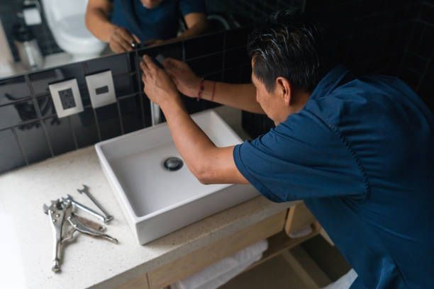 A man is fixing a sink in a bathroom.