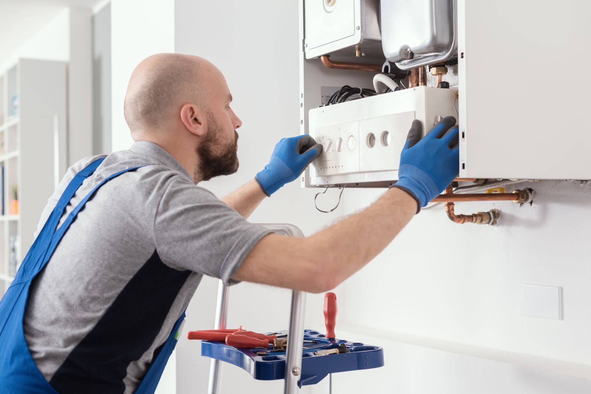 A man is working on a boiler in a kitchen.