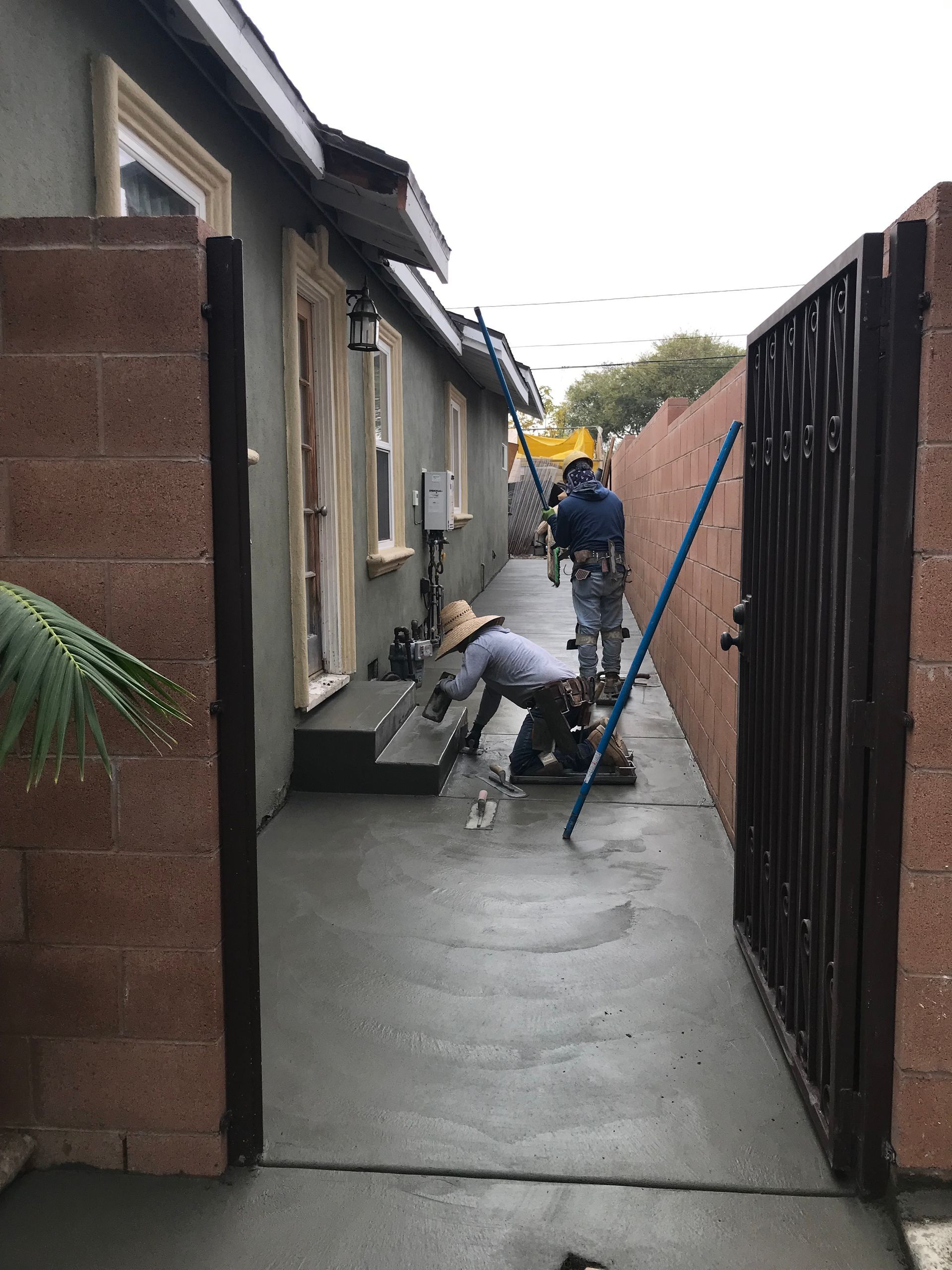 Freshly poured concrete sidewalk and driveway apron under construction on a sunny street.