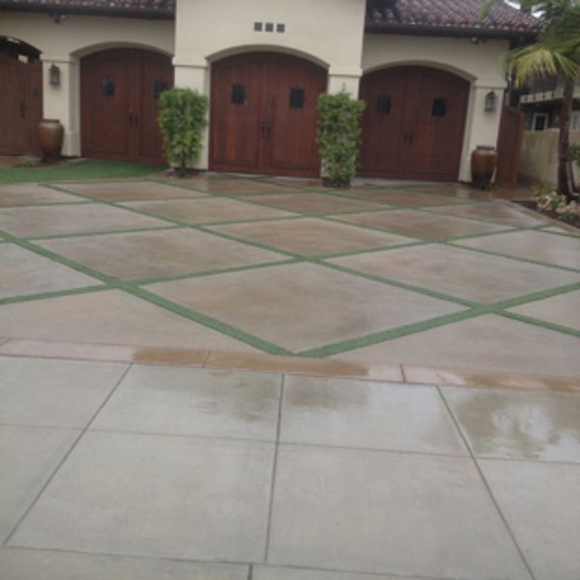 A front yard in progress with a new concrete paver walkway, mulch landscaping, and a small excavator in the background.