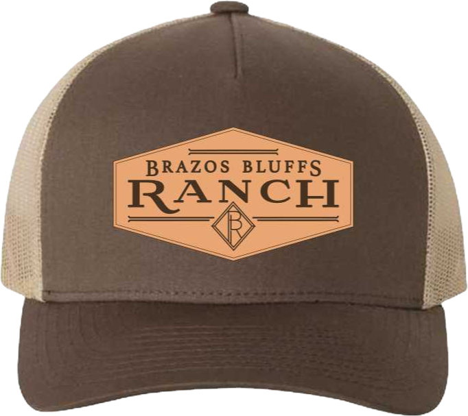 Camouflage trucker hat with a tan leather patch reading 