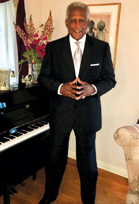 Houston personal injury attorney in a suit and tie standing in front of a piano