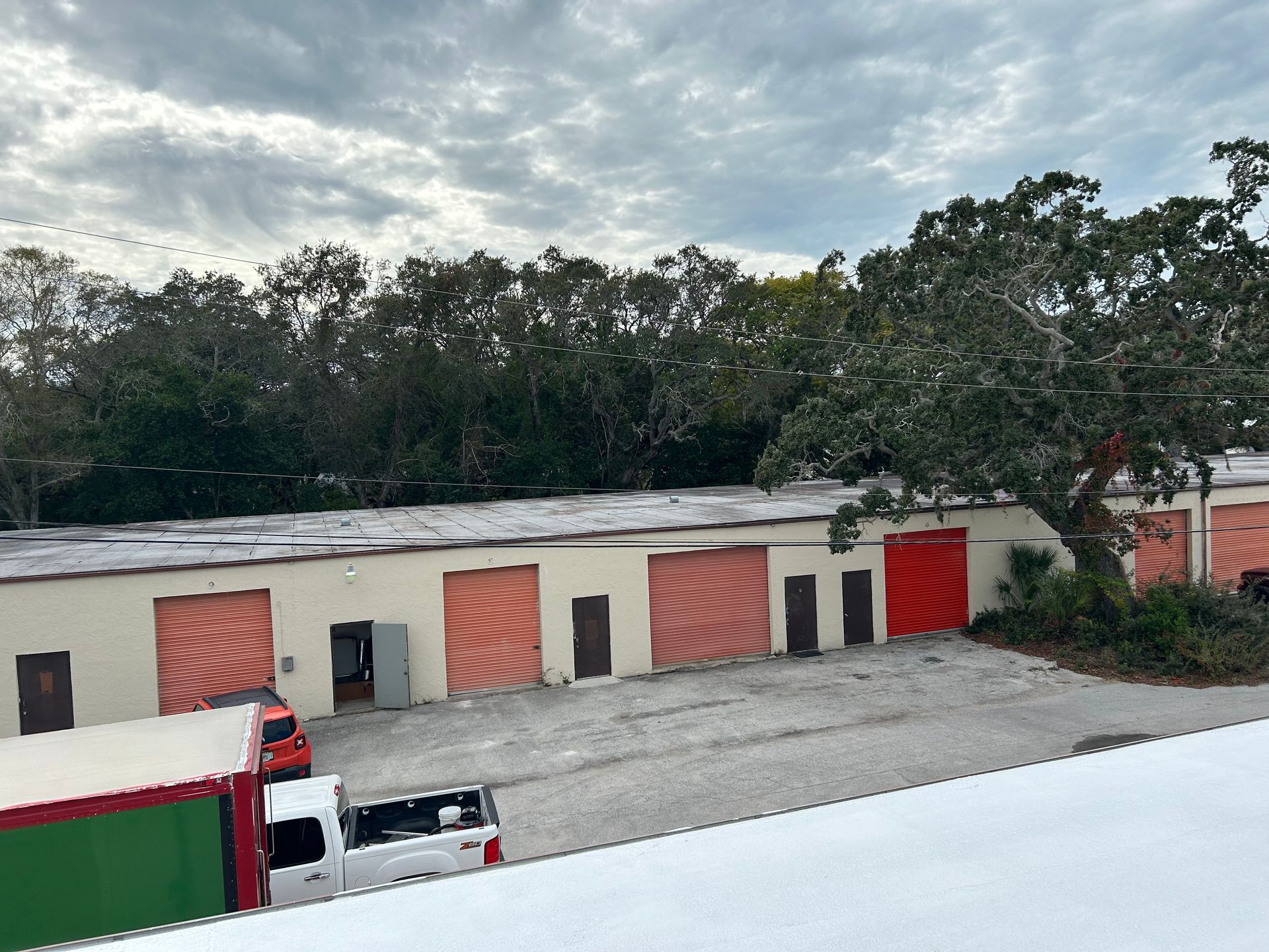 A truck is parked in front of a building with red garage doors.
