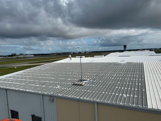 A large white roof of a building with a cloudy sky in the background.
