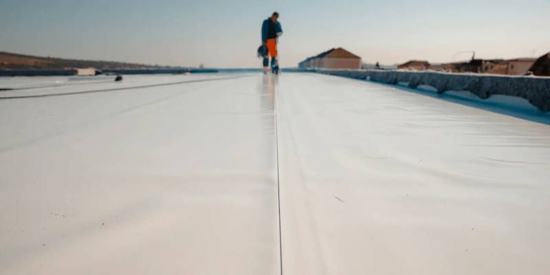 A man is standing on top of a white roof.