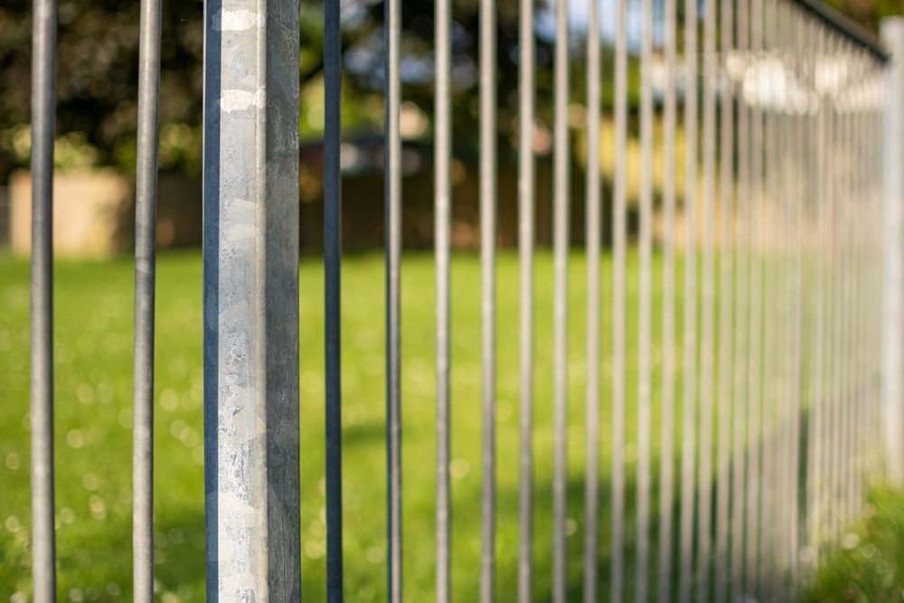 Metal fence posts and vertical bars with green grass and blurred background. — True North Fencing In Noonamah, NT