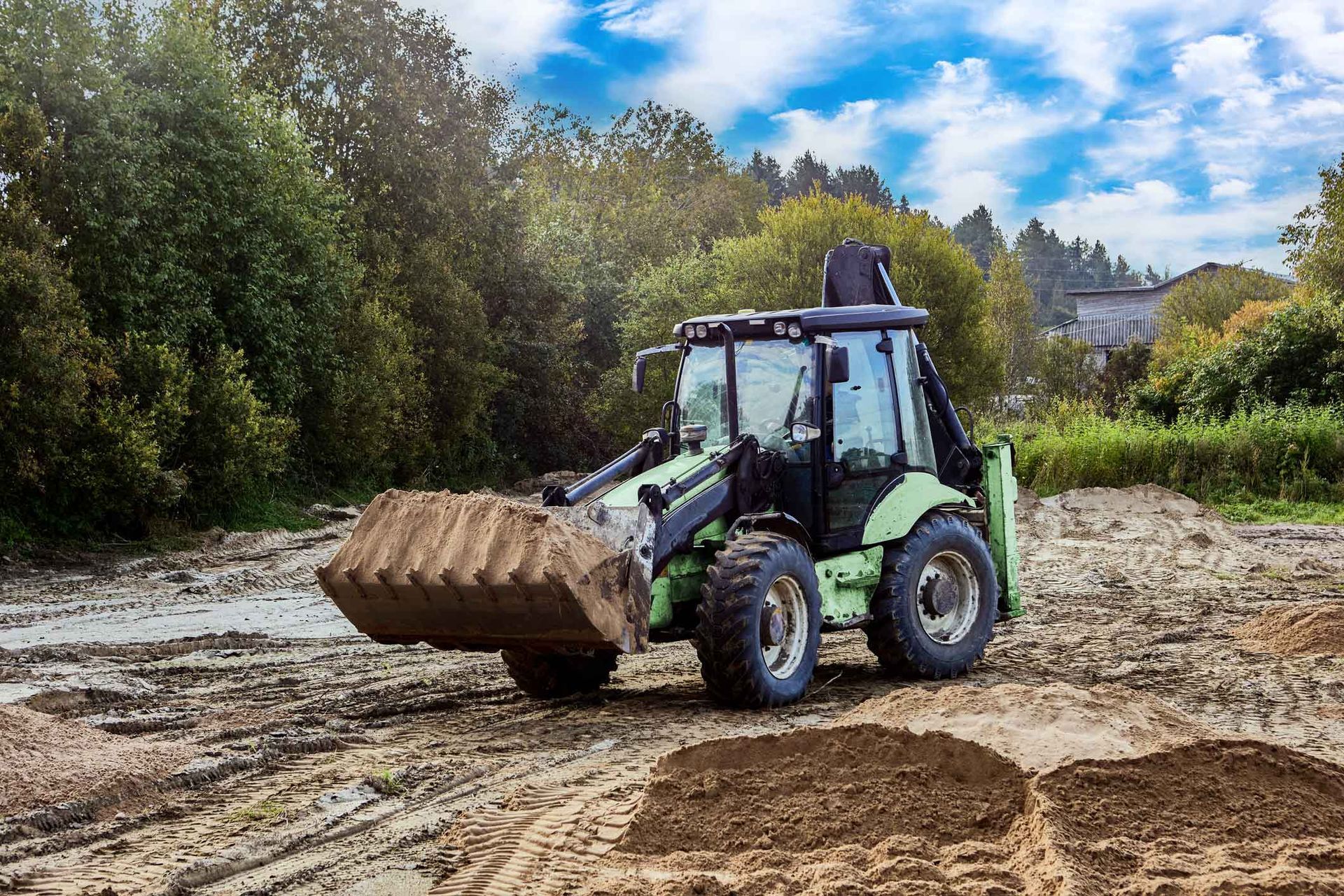 A wheel-mounted earthmover spreading soil evenly to create a stable base for a construction site.