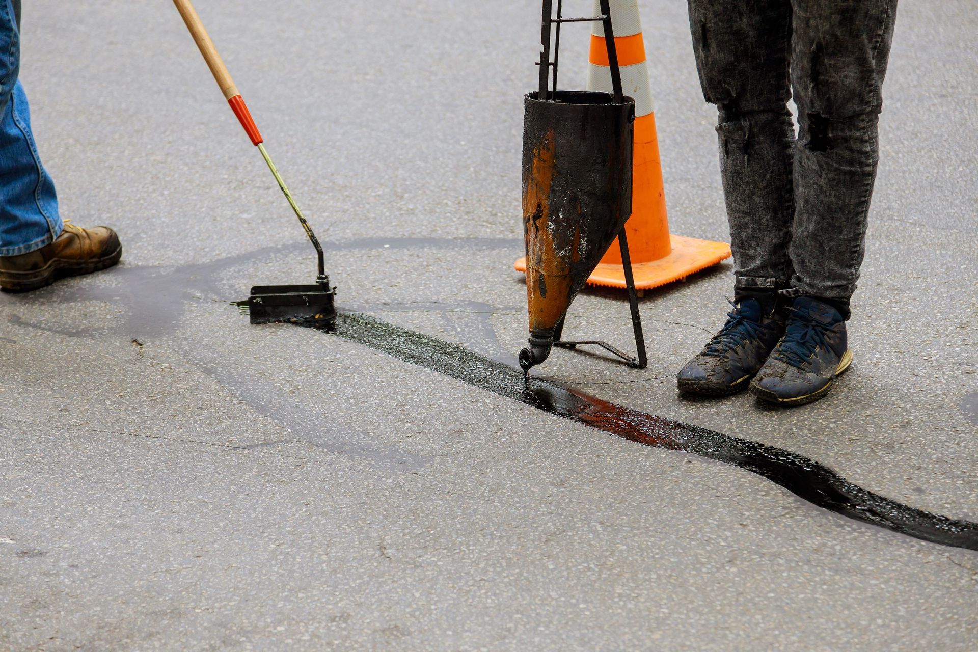 Two workers sealing joint crack in asphalt for road surface restoration work. Two workers sealing joint crack in asphalt for road surface restoration work.