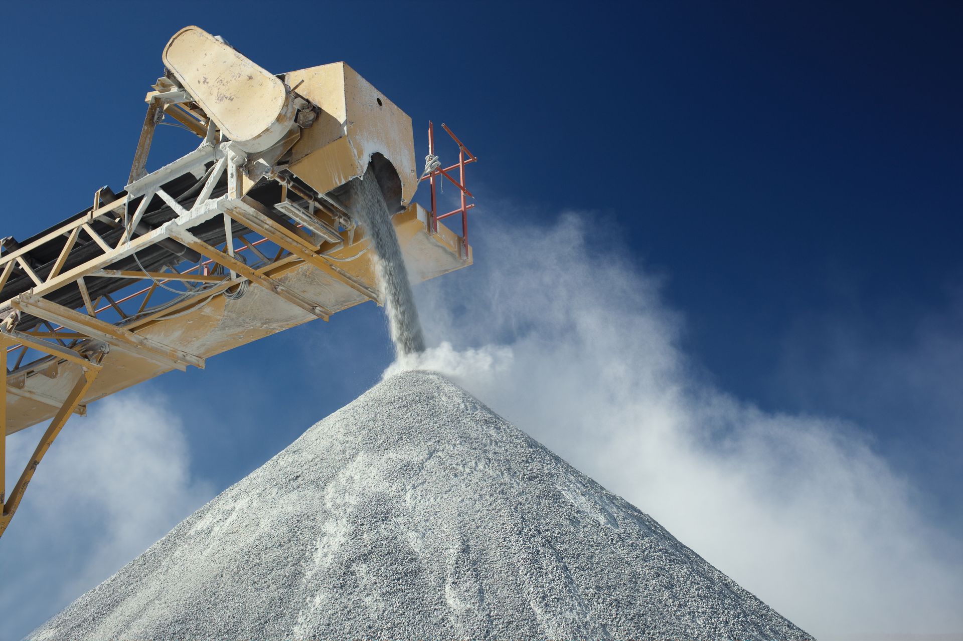 Details of rock stone crushing equipment in a limestone quarry against a dark blue sky.