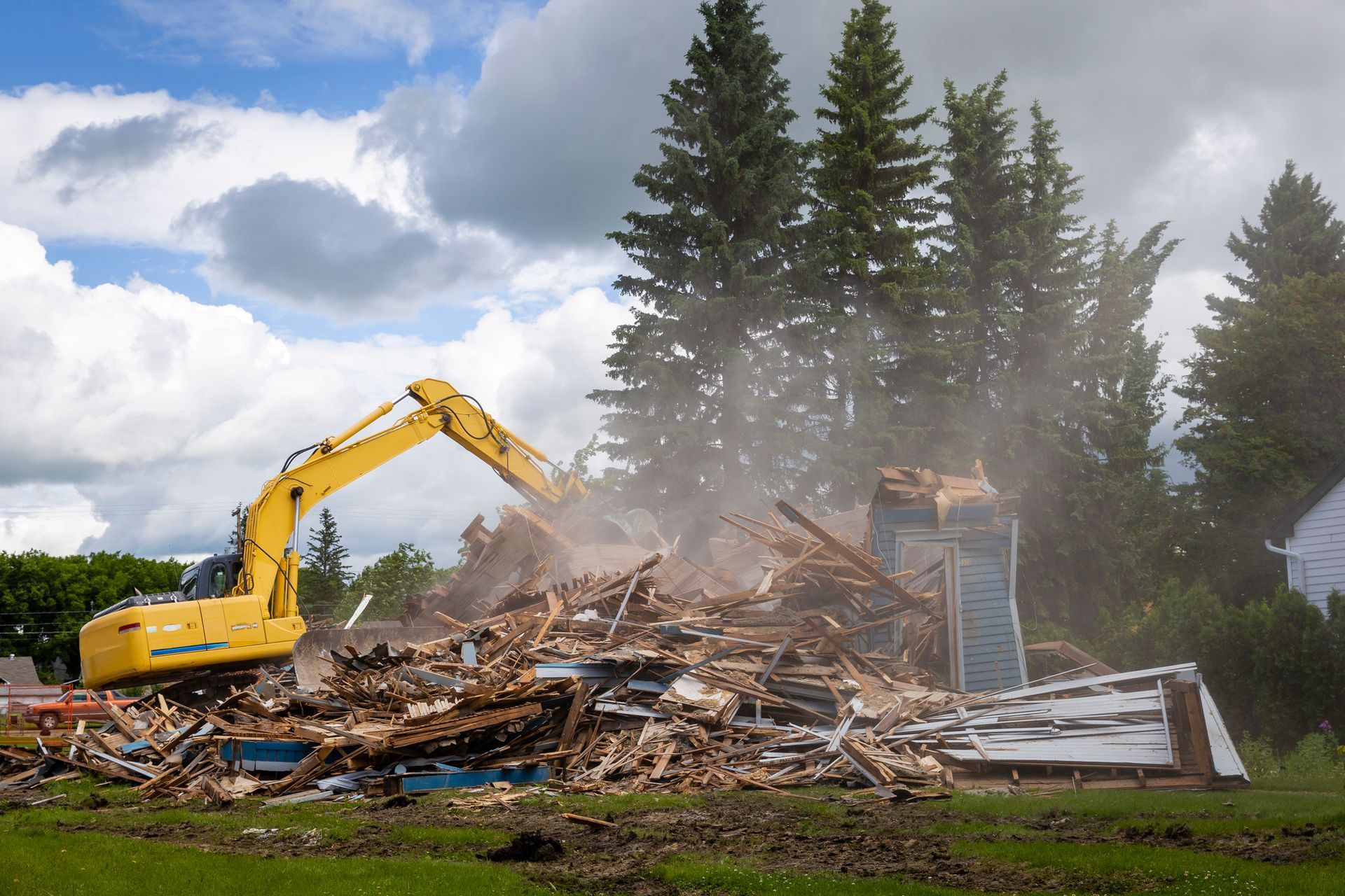 Heavy duty machine demolishing a wood building.