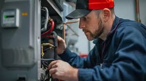 Man in blue uniform and cap working on HVAC system