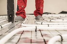 Person in red overalls installing radiant floor heating tubes for a radiant floor heating system. 