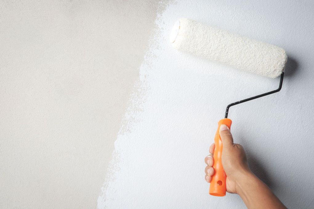 A person is painting a wall with a paint roller.