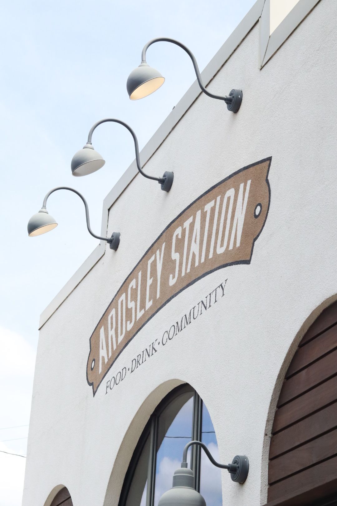 Street sign reading “Arosel Station” on a white building with arched windows and exterior lamps