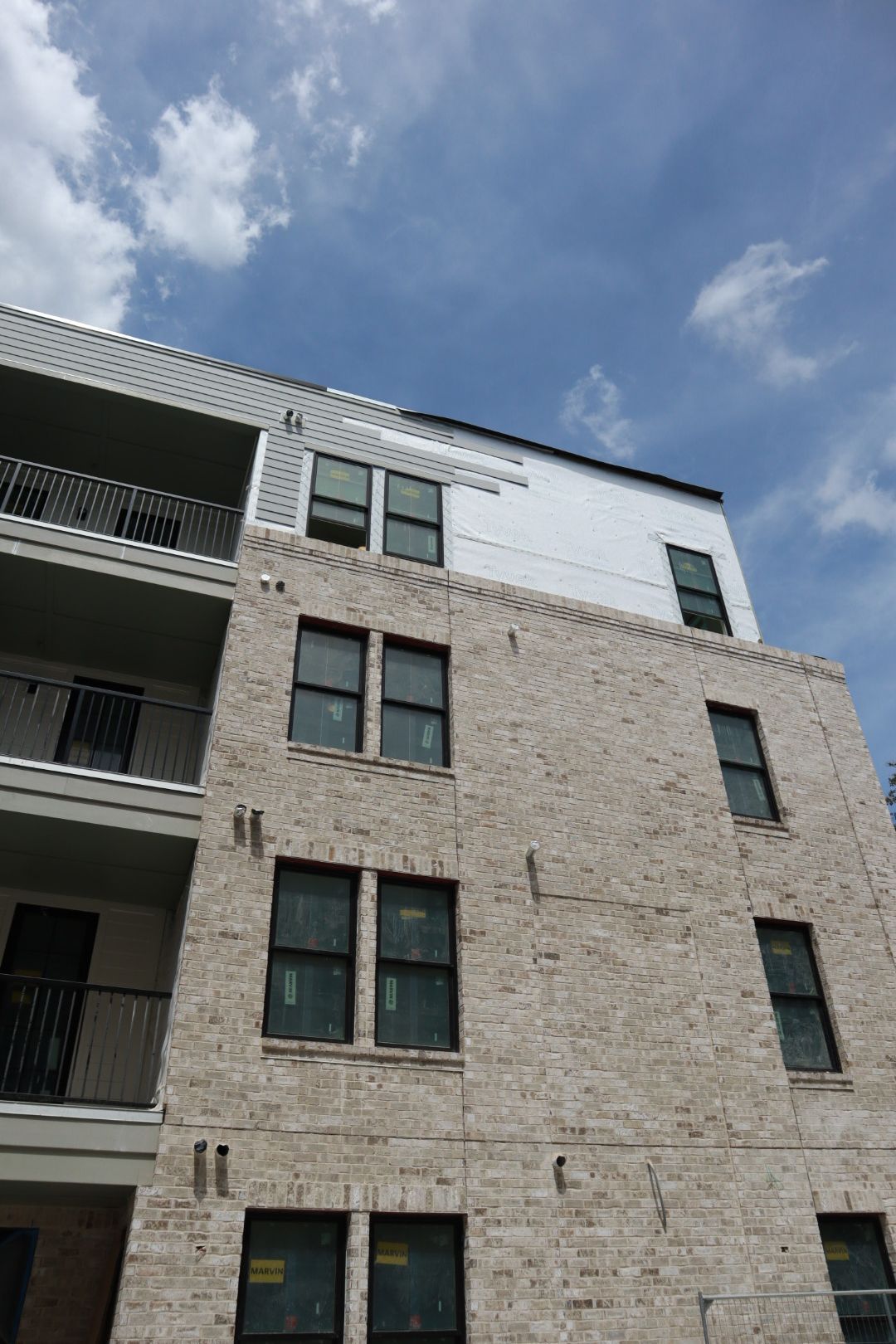 Multi-story brick apartment building with dark windows against a blue sky