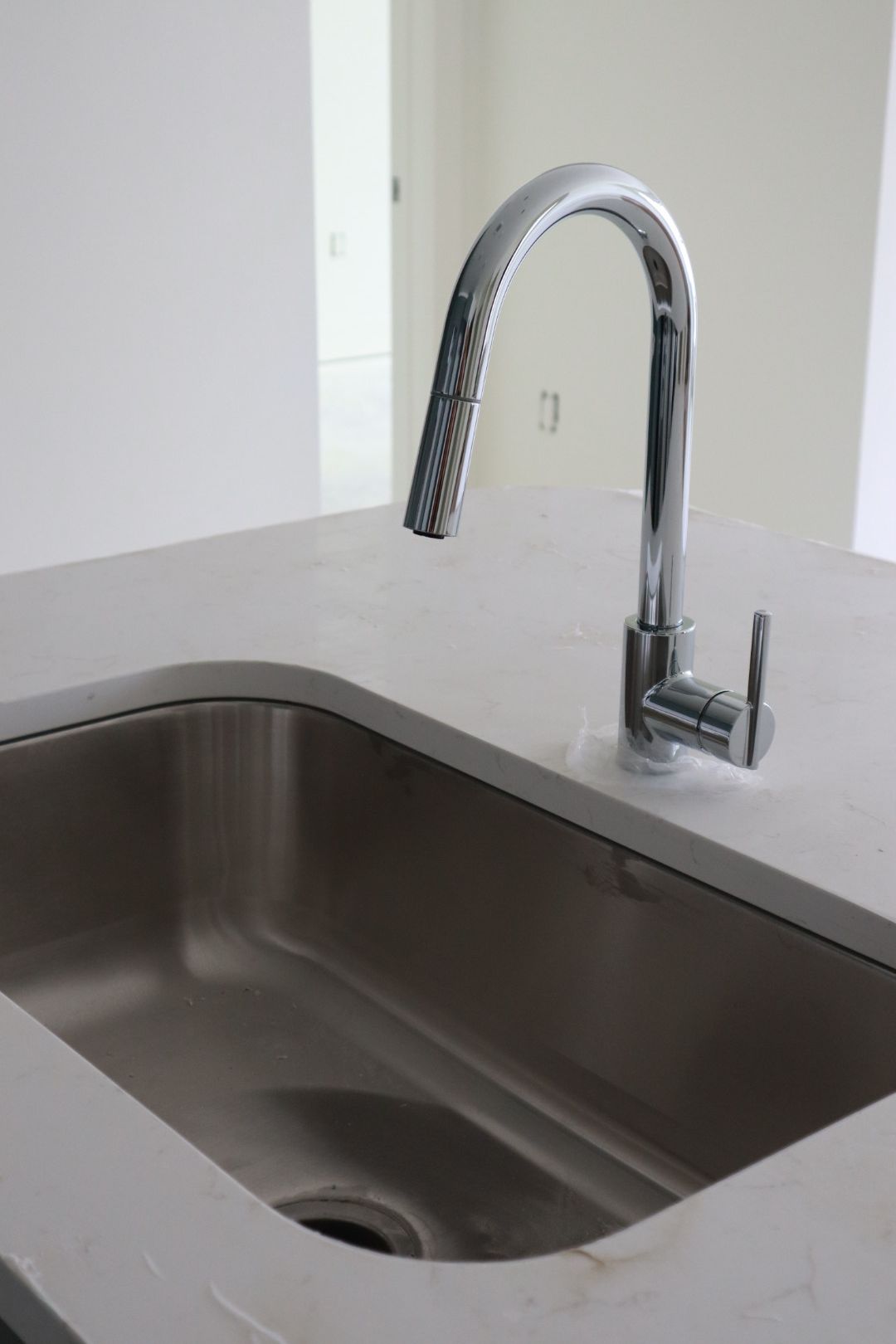 Stainless steel kitchen sink with a chrome faucet on a light countertop.