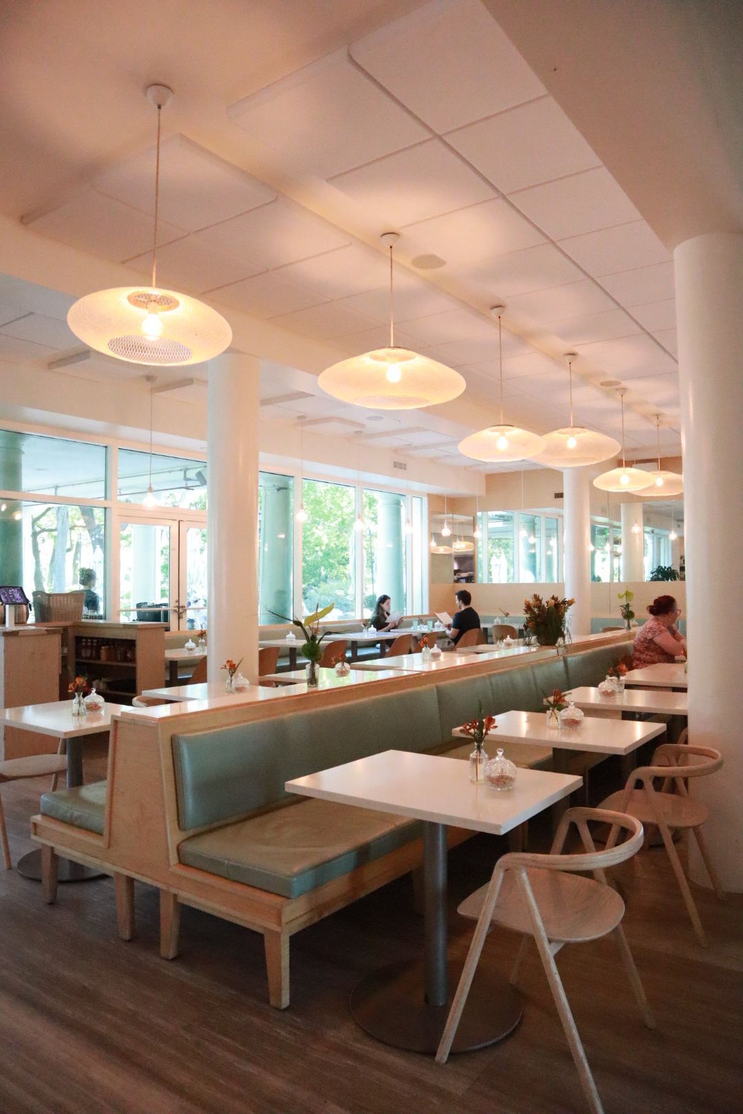 Bright, modern café interior with booth seating, pendant lights, and large windows overlooking greenery