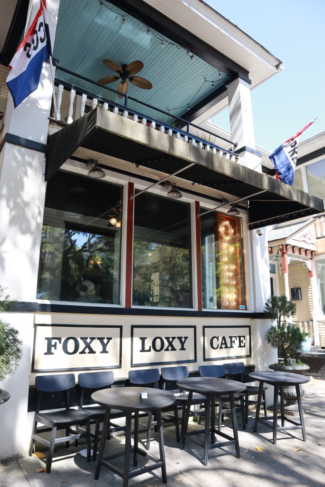 Outdoor FOXY LOXY CAFE with tables and chairs under a shaded balcony