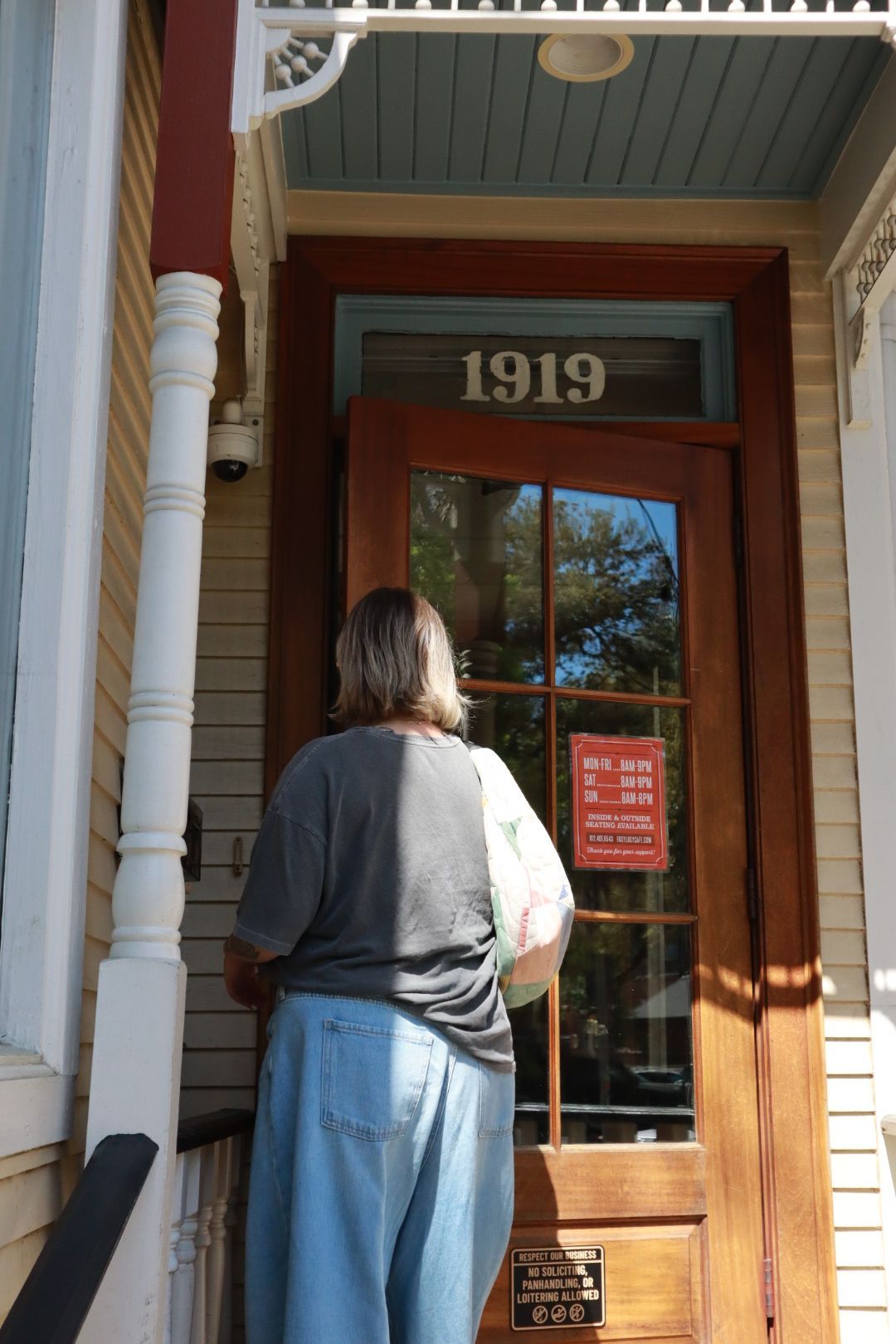 Person standing at a wooden storefront door numbered 1919