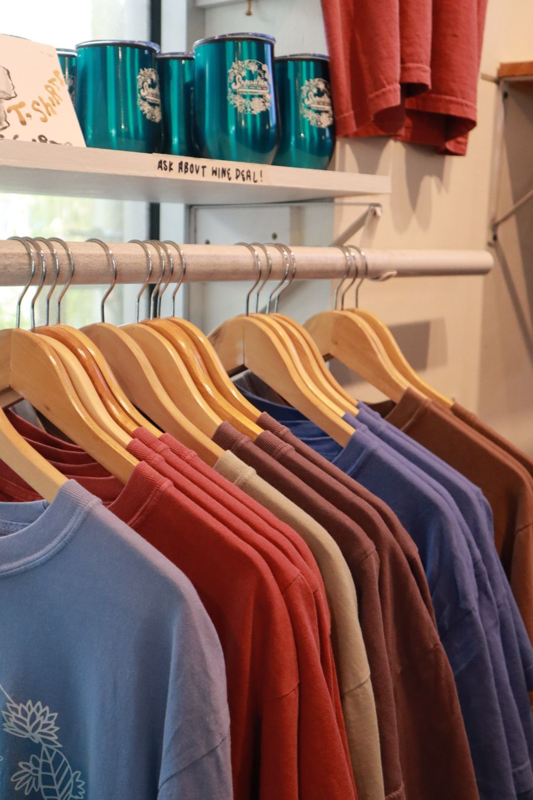 Clothing rack with colorful shirts on wooden hangers in a boutique