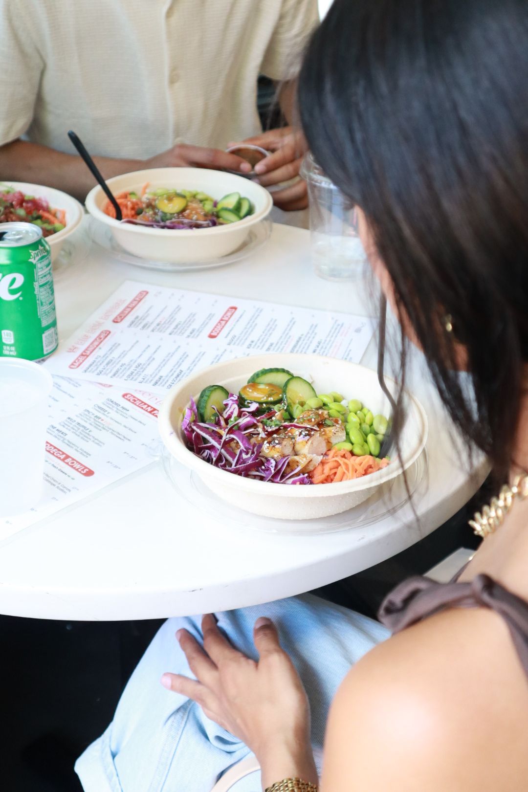 People eating salad at a small round table with drinks and menus