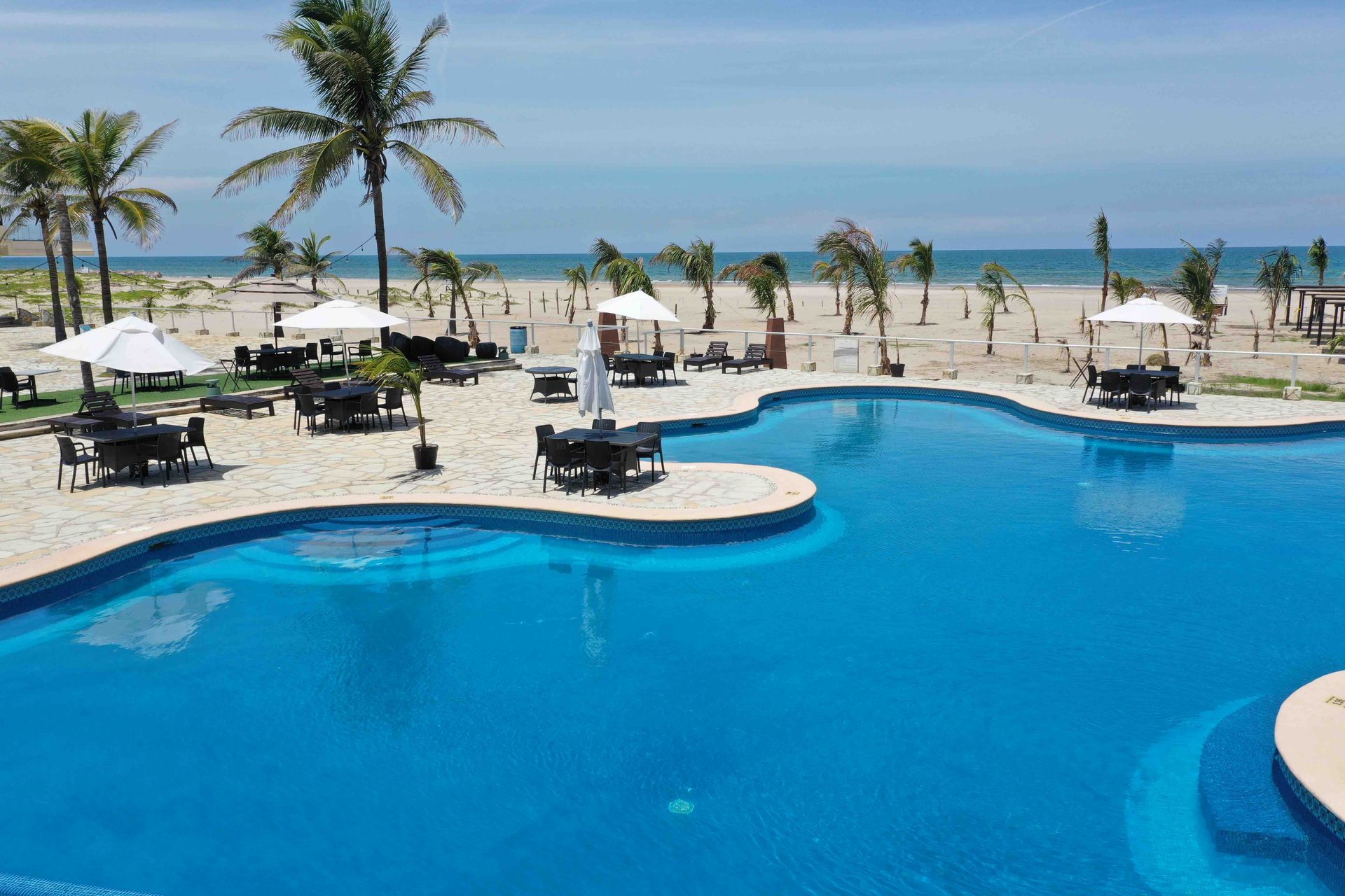 There is a large swimming pool in the middle of the beach.