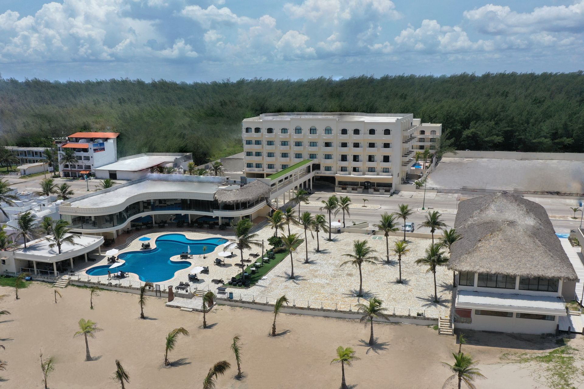 An aerial view of a hotel with a large pool and palm trees