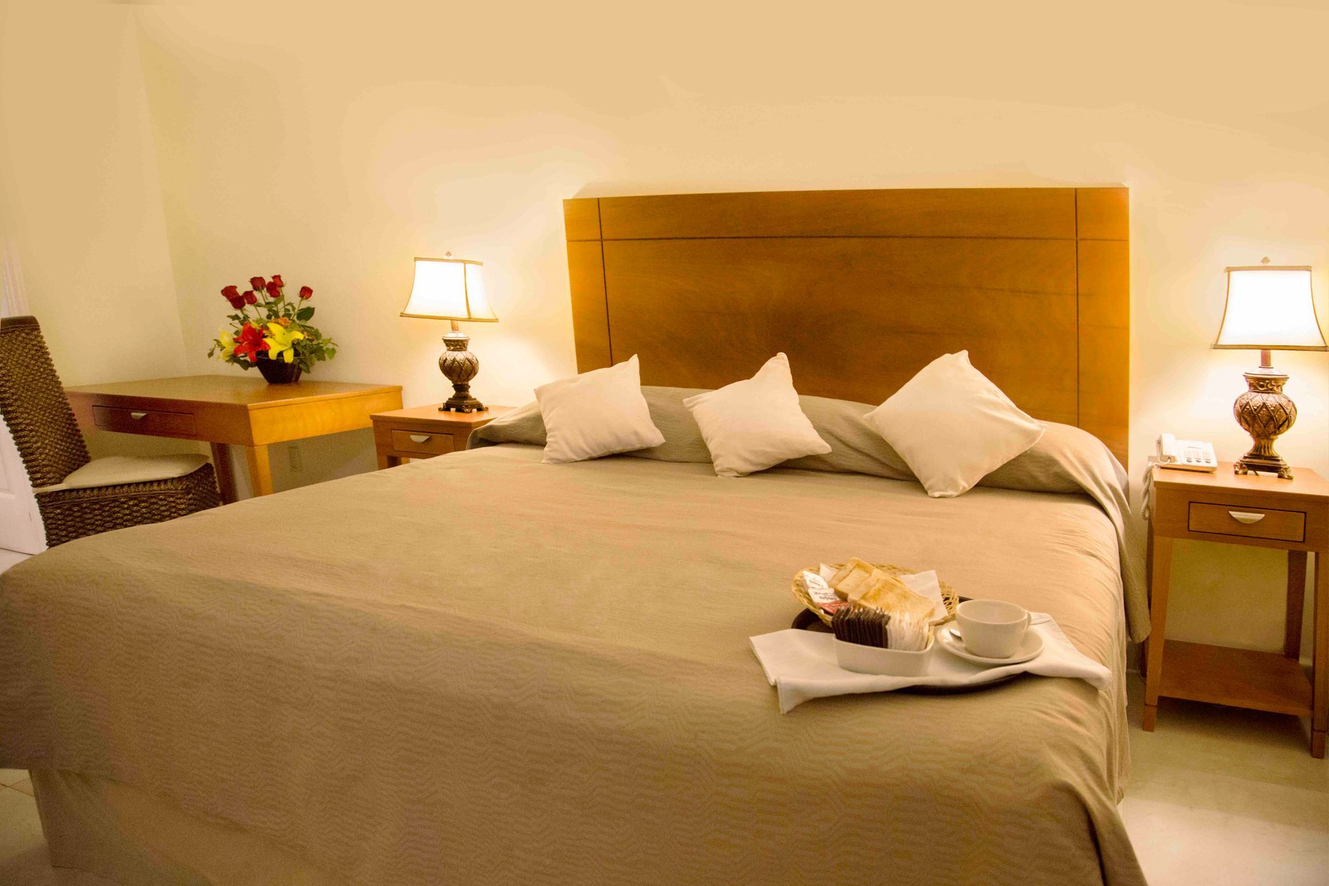 A hotel room with a tray of food on the bed