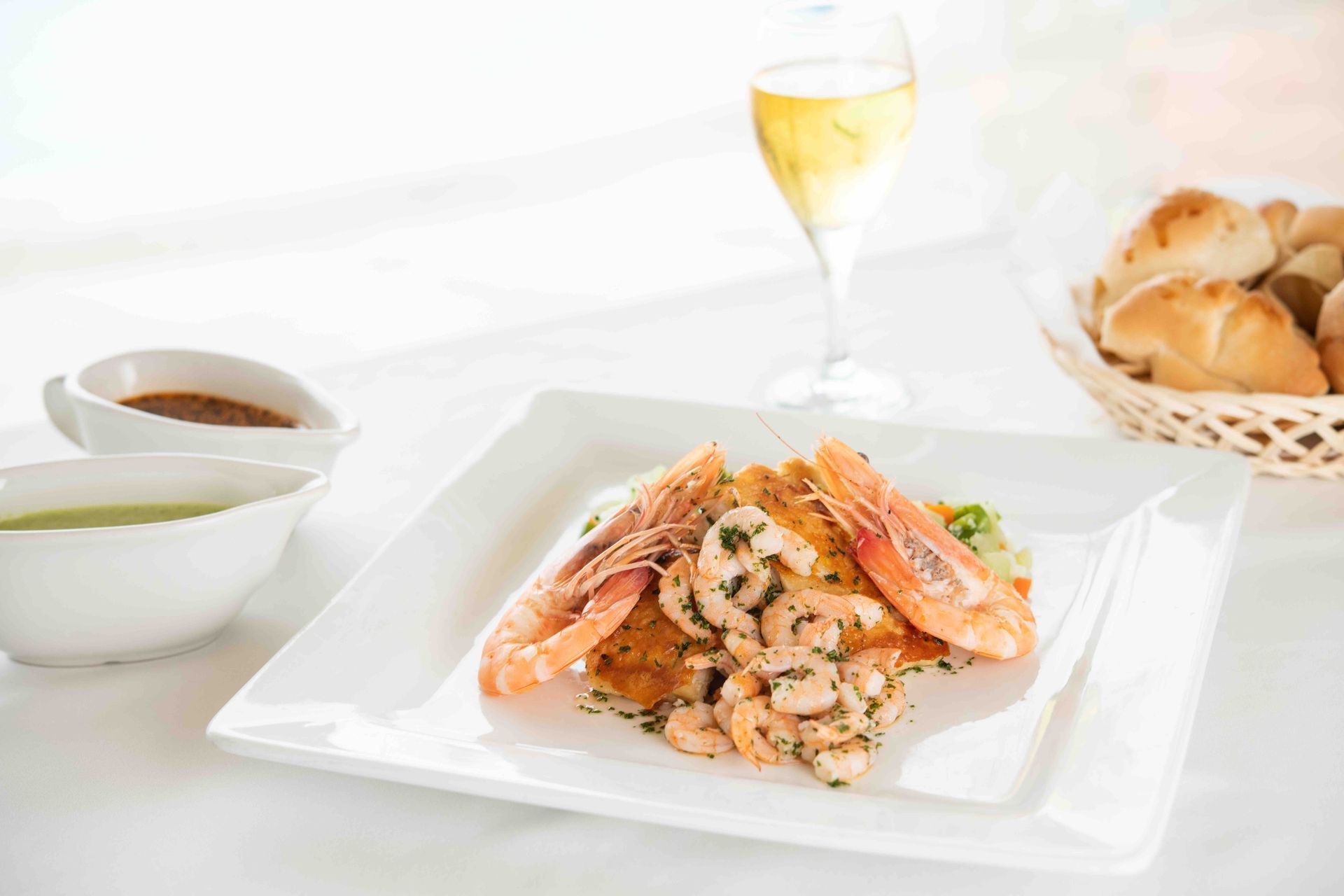 A plate of food with shrimp and a glass of wine on a table.
