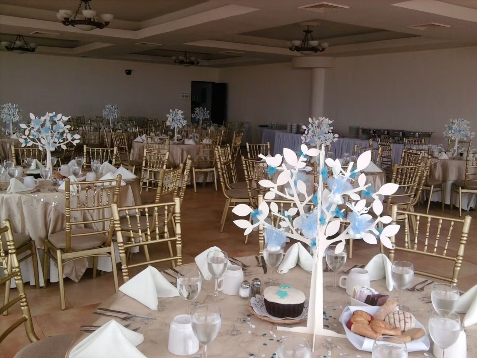 A large room with tables and chairs set up for a wedding reception