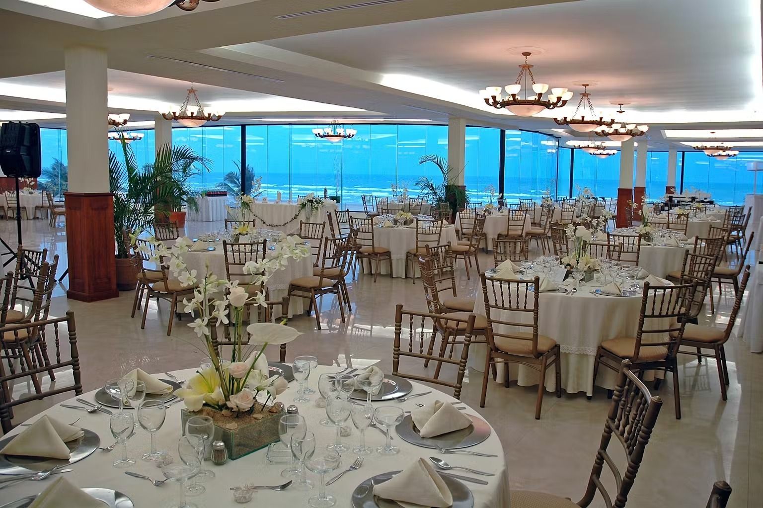 A large room with tables and chairs set up for a wedding reception