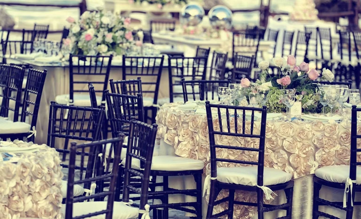 A row of tables and chairs set up for a wedding reception.