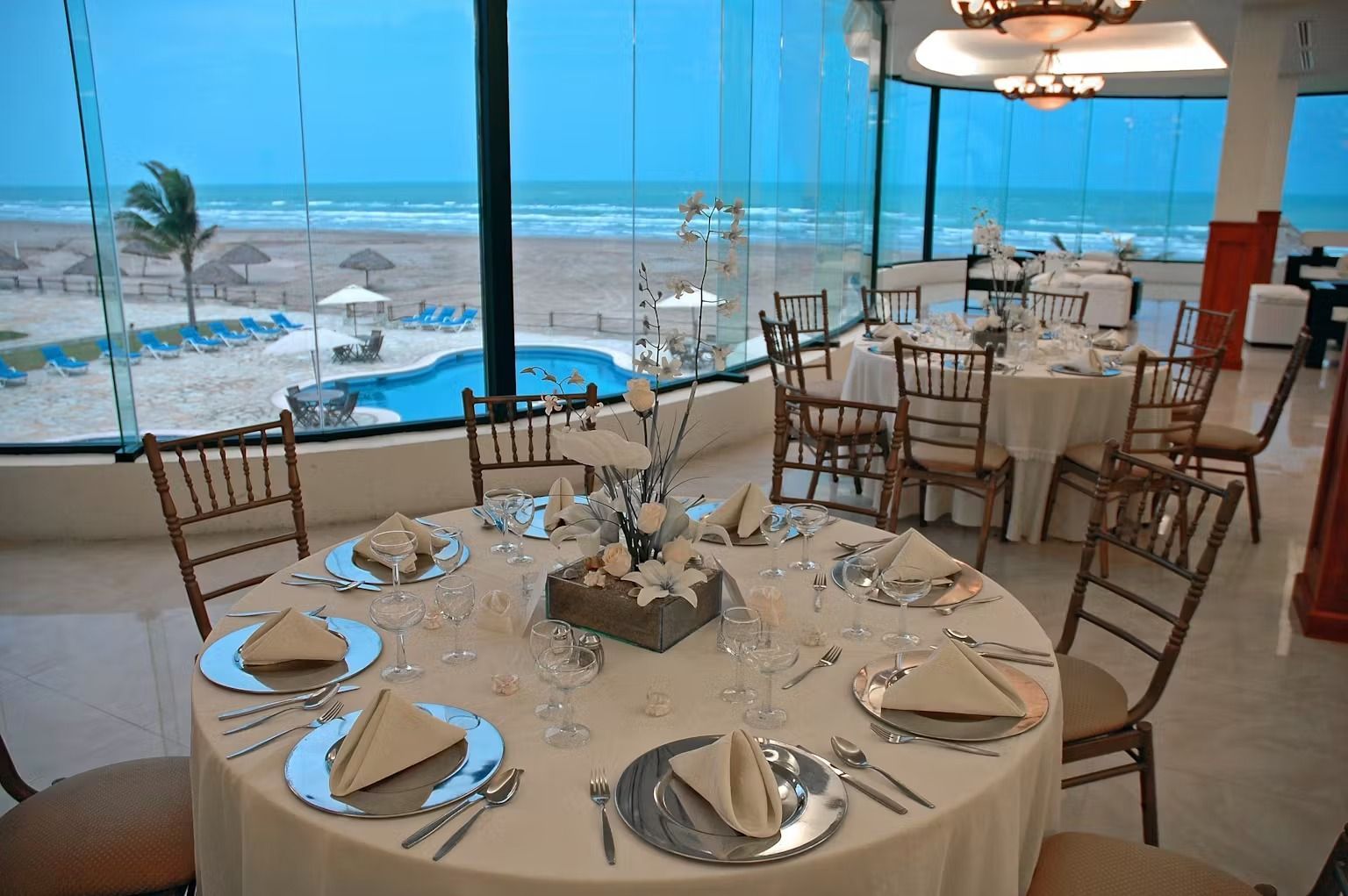 A dining room with tables and chairs and a view of the ocean.