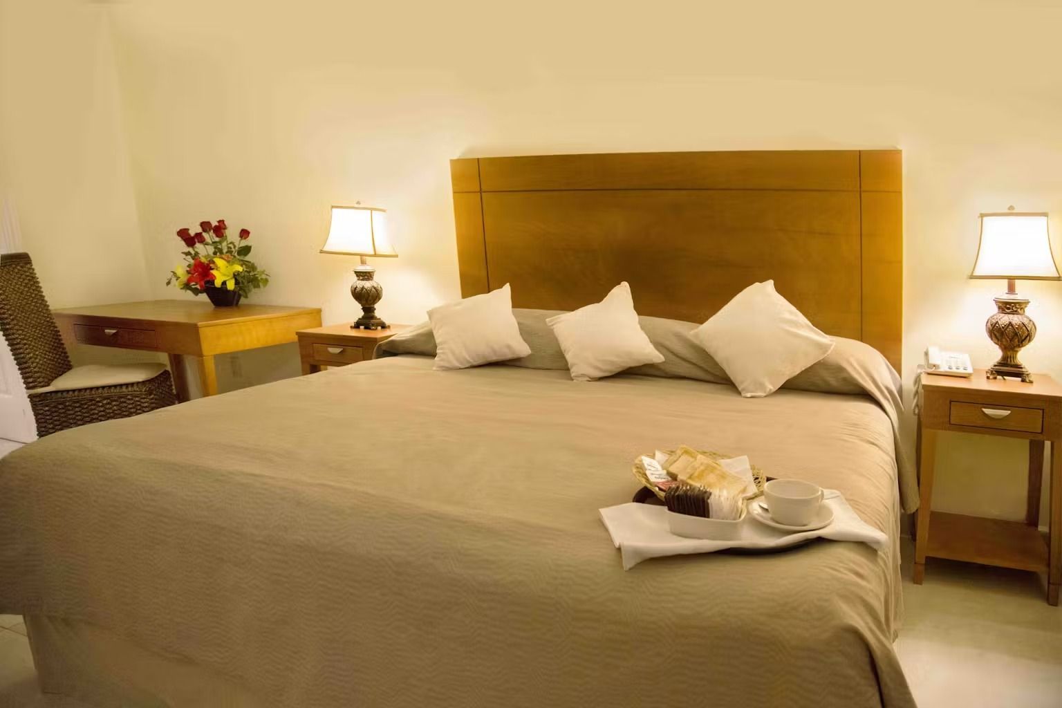 A hotel room with a tray of food on the bed