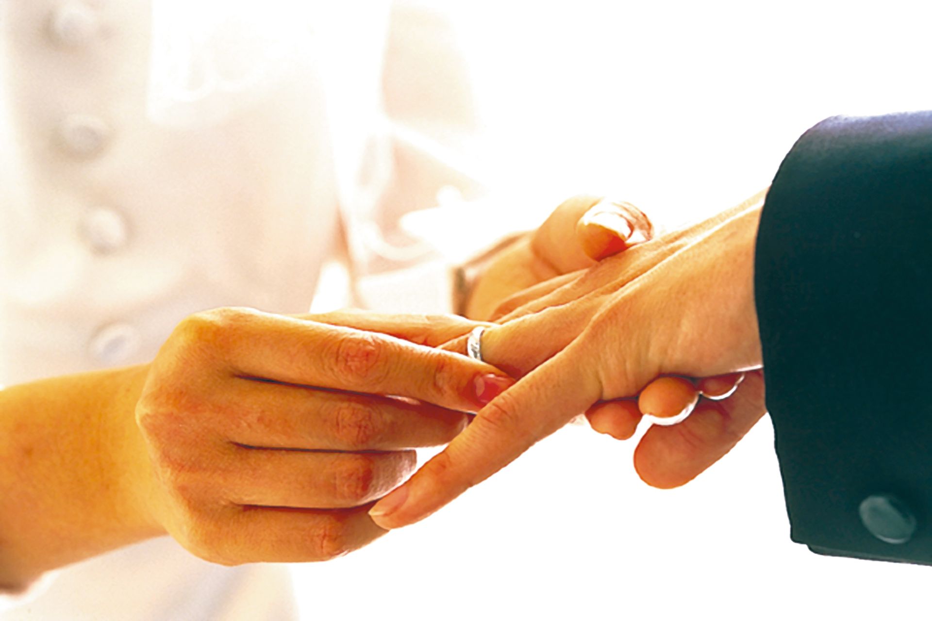 Person placing a ring on another person's finger, representing marriage immigration.