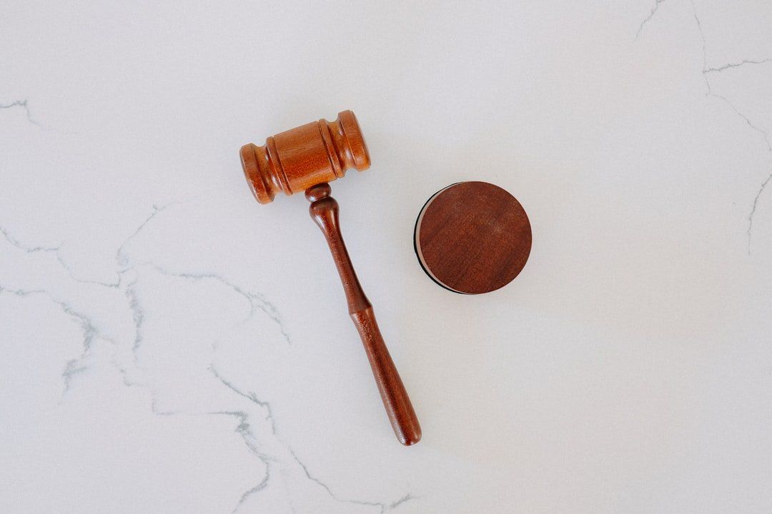 Wooden gavel and sound block on a white marble surface.
