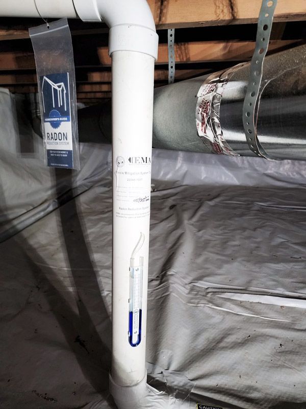 A white pipe with a blue u on it is in a basement.