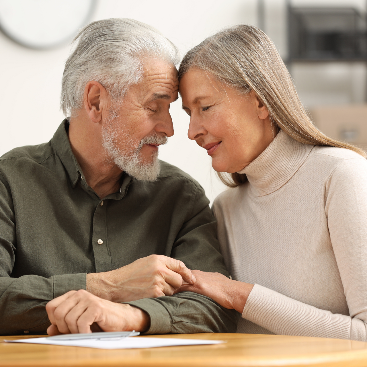 Elderly couple touching foreheads, looking at each other, in a tender moment.