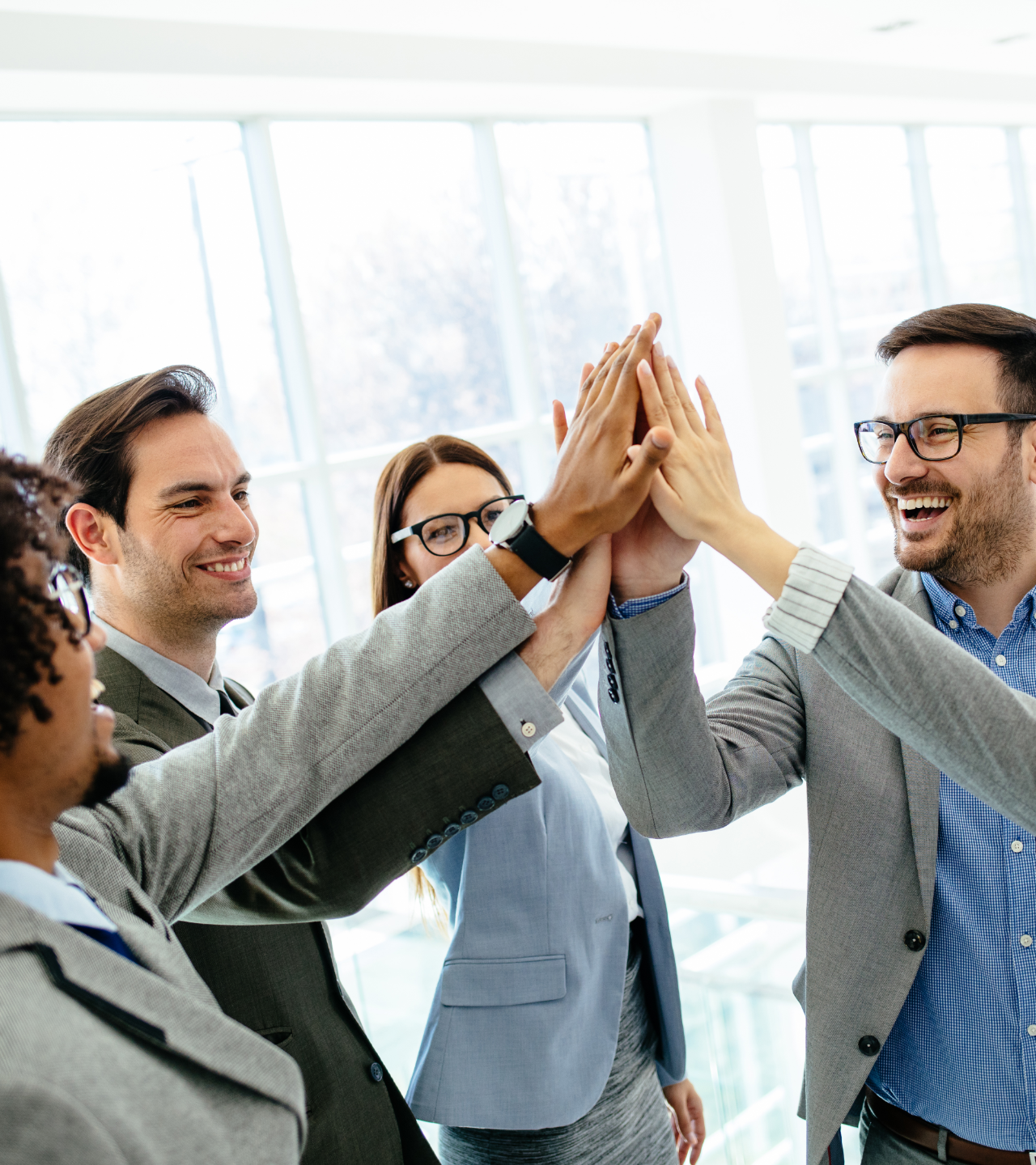 Business team high-fiving in a bright office, celebrating success.