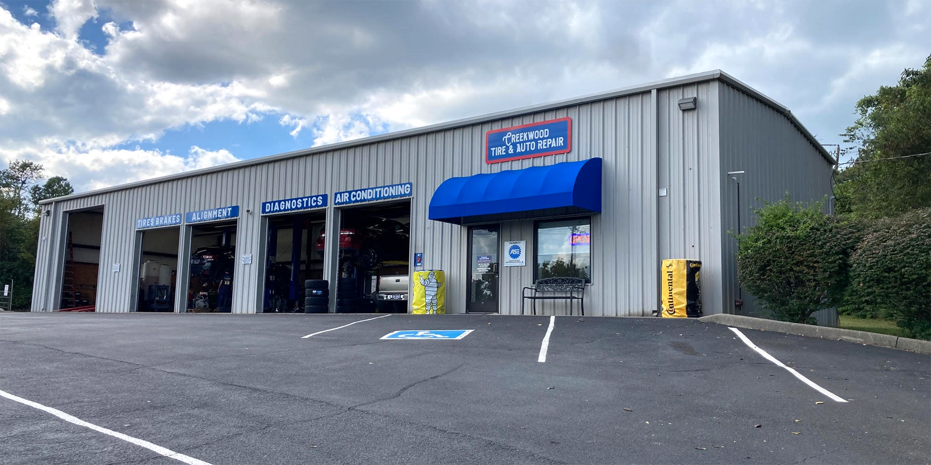 a large metal building with a blue awning and a parking lot in front of it .