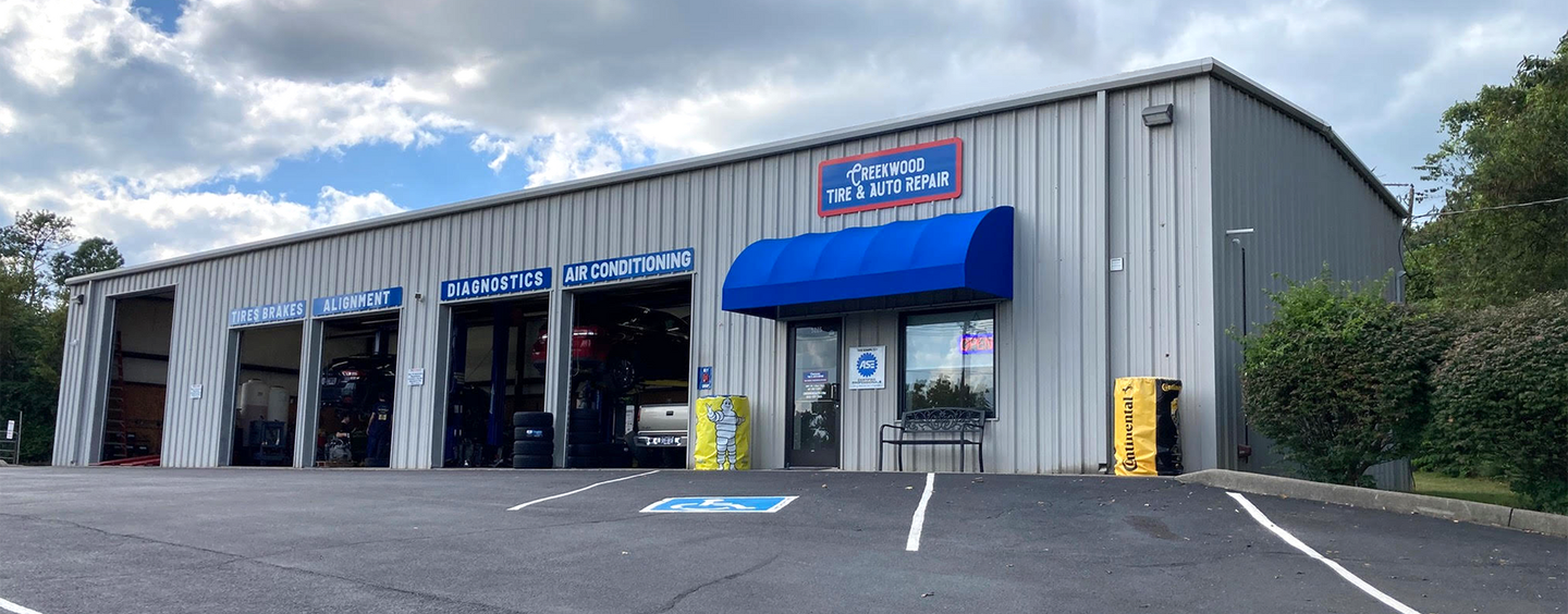 a large metal building with a blue awning and a parking lot in front of it .