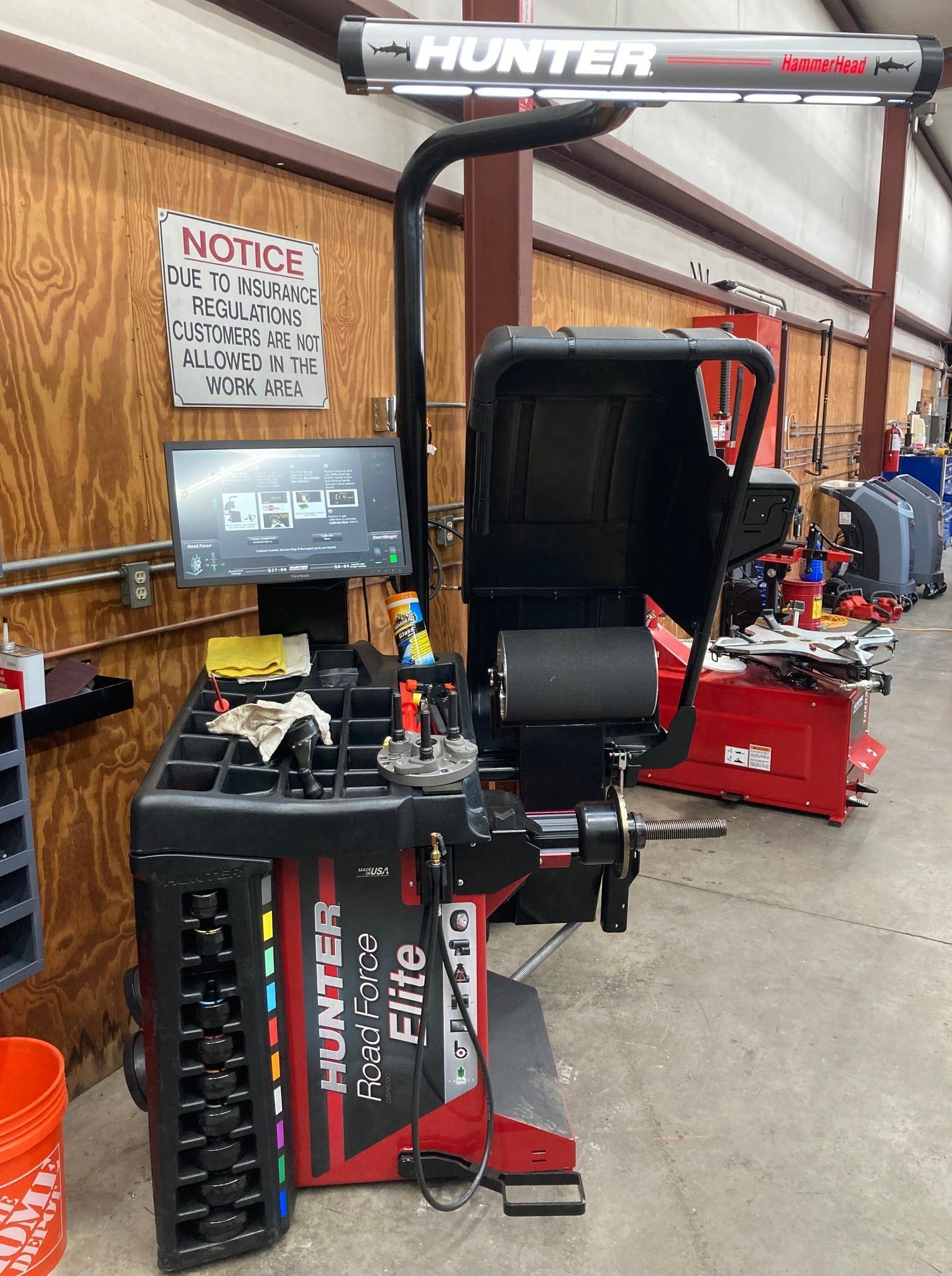 a tire balancing machine is sitting in a garage next to a sign that says notice .